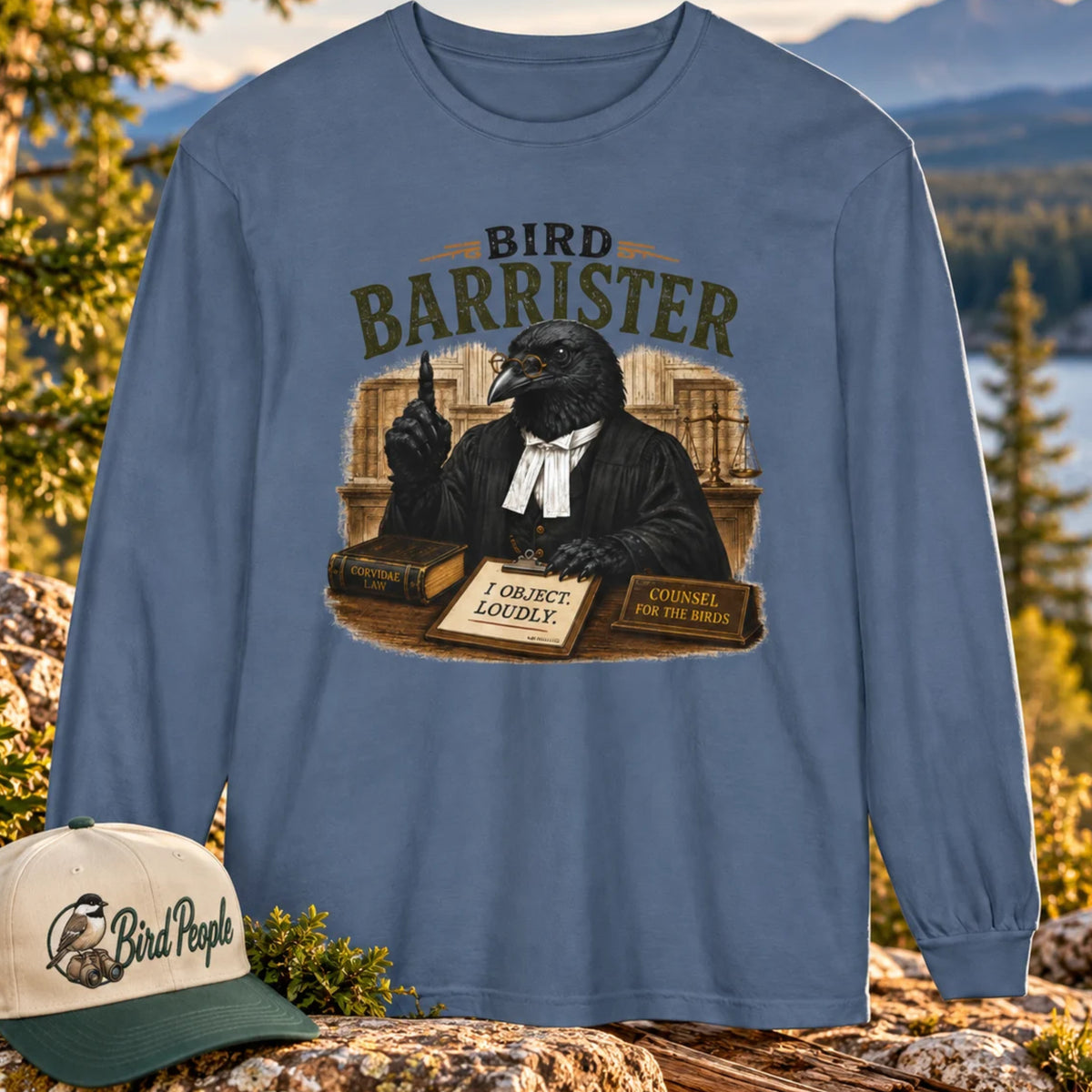 Bird Barrister crow long sleeve t-shirt in Blue Jean denim blue, outdoors on a rocky mountain overlook with a Bird Peeple chickadee trucker hat — funny lawyer crow design for birdwatchers.